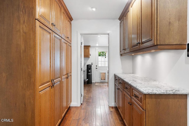interior space featuring brown cabinetry, light stone countertops, recessed lighting, and hardwood / wood-style floors