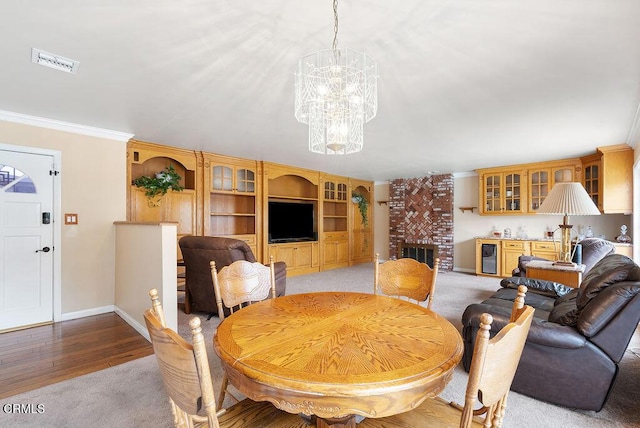 dining space with visible vents, crown molding, a brick fireplace, baseboards, and a chandelier