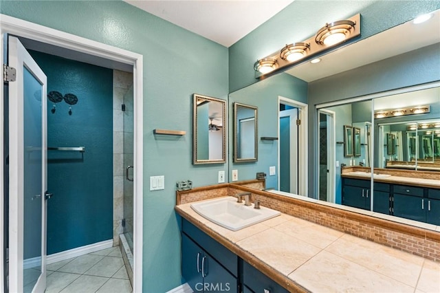 full bathroom with baseboards, a shower stall, tile patterned flooring, and vanity