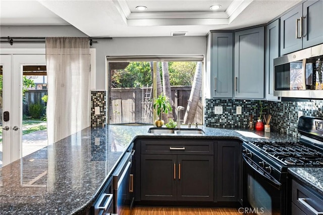 kitchen featuring stainless steel microwave, decorative backsplash, black gas stove, and a sink