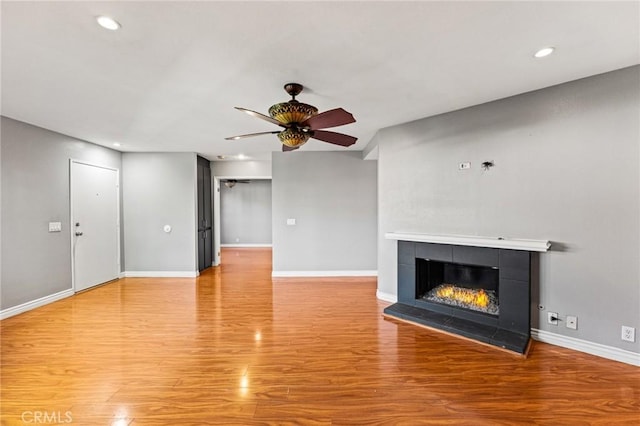 unfurnished living room featuring light wood-style flooring, baseboards, recessed lighting, ceiling fan, and a fireplace