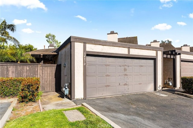 garage with fence and aphalt driveway