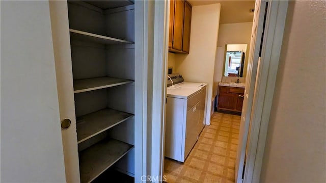 clothes washing area with cabinet space, washing machine and clothes dryer, a sink, and light floors