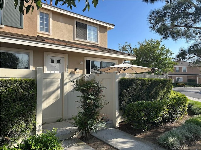 exterior space featuring stucco siding and fence