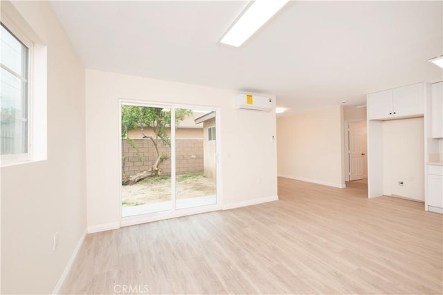 1181 W 4th St, Pomona, CA 91766 - unfurnished living room with a wall mounted AC, light wood finished floors, and baseboards