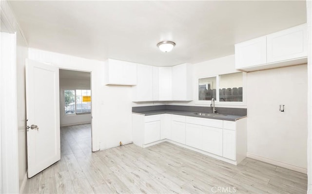 1181 W 4th St, Pomona, CA 91766 - kitchen featuring dark countertops, light wood-style flooring, white cabinetry, and a sink