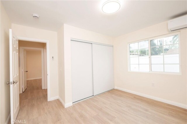 1181 W 4th St, Pomona, CA 91766 - unfurnished bedroom featuring baseboards, light wood-style flooring, an AC wall unit, and a closet
