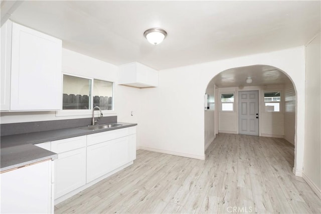 1181 W 4th St, Pomona, CA 91766 - kitchen featuring arched walkways, dark countertops, a sink, and light wood-style floors