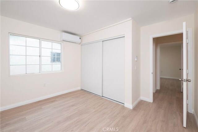 1181 W 4th St, Pomona, CA 91766 - unfurnished bedroom with baseboards, light wood-type flooring, a closet, and a wall unit AC