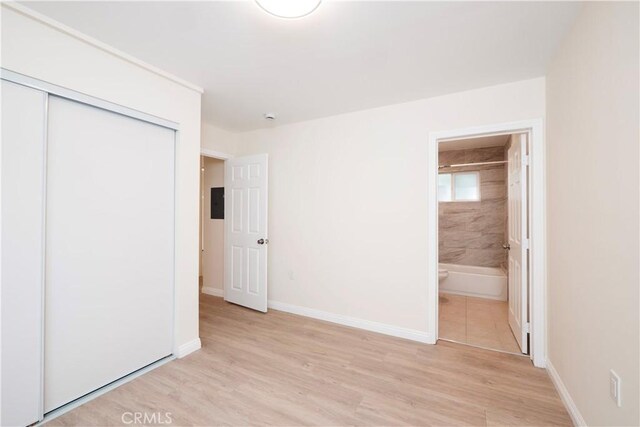 1181 W 4th St, Pomona, CA 91766 - unfurnished bedroom with ensuite bath, light wood-style flooring, a closet, and baseboards