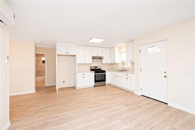 1181 W 4th St, Pomona, CA 91766 - kitchen with stainless steel range with gas cooktop, a sink, a wall unit AC, light wood-style floors, and under cabinet range hood
