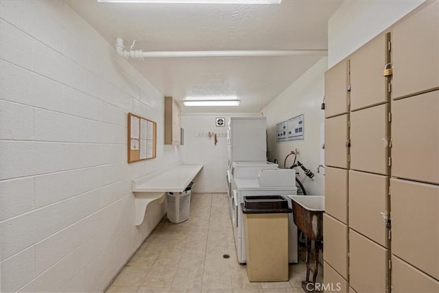 laundry room featuring cabinet space, light tile patterned flooring, washing machine and dryer, and concrete block wall