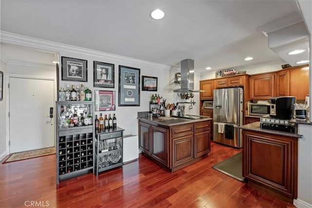 kitchen featuring appliances with stainless steel finishes, wall chimney exhaust hood, dark countertops, brown cabinetry, and dark wood finished floors