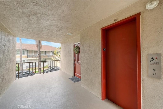 doorway to property with elevator, stucco siding, and a balcony