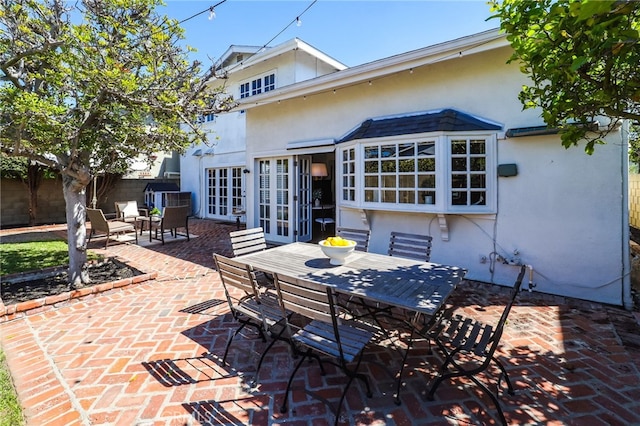 back of house featuring stucco siding, fence, a patio area, french doors, and outdoor dining space
