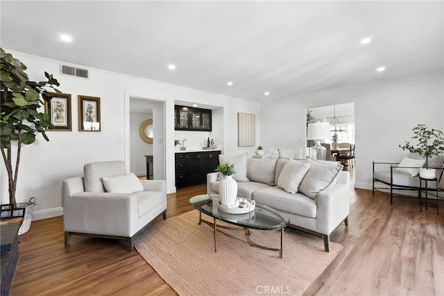 living area featuring bar, light wood finished floors, visible vents, and recessed lighting