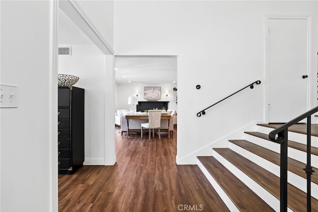 stairway featuring visible vents, baseboards, wood finished floors, and a fireplace