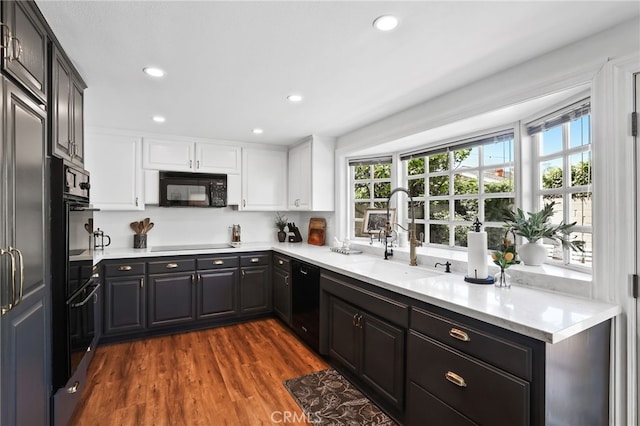 kitchen featuring light countertops, a healthy amount of sunlight, a sink, and black appliances