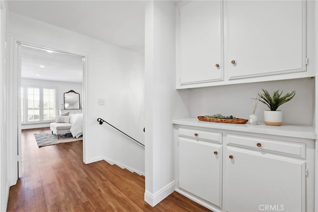 corridor with wood finished floors, baseboards, and an upstairs landing