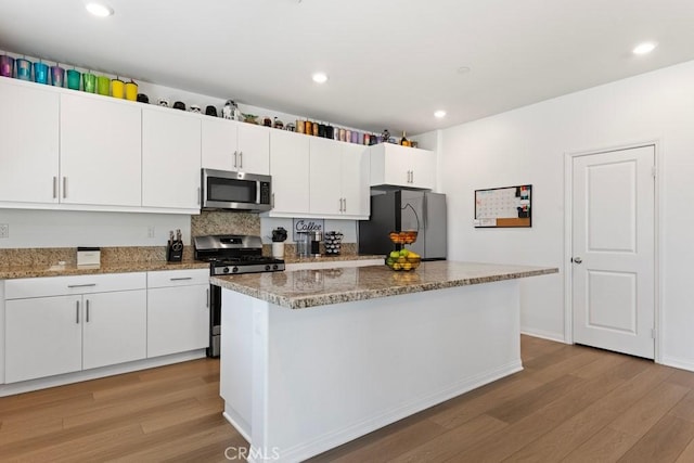 5085 Hoss Cir, Hemet, CA 92545 - kitchen featuring appliances with stainless steel finishes, light wood finished floors, white cabinetry, a kitchen island, and light stone countertops