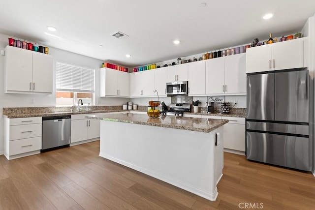 5085 Hoss Cir, Hemet, CA 92545 - kitchen featuring stainless steel appliances, white cabinetry, light wood-type flooring, a center island, and stone counters