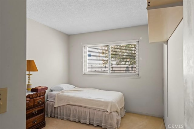 bedroom featuring light carpet and a textured ceiling