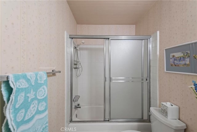 full bath with wallpapered walls, toilet, and bath / shower combo with glass door
