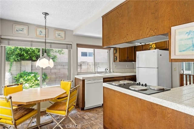 kitchen featuring a textured ceiling, a sink, white appliances, and light countertops