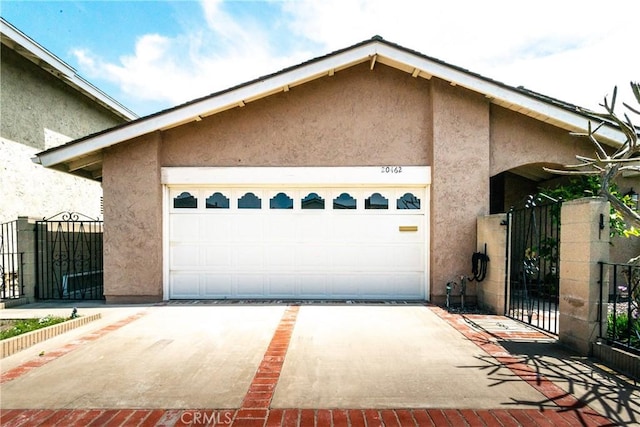 garage featuring a gate, concrete driveway, and fence