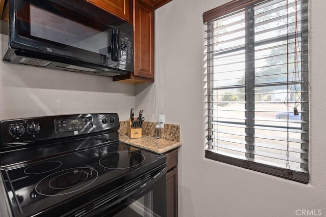 kitchen with a wealth of natural light, brown cabinets, and black appliances