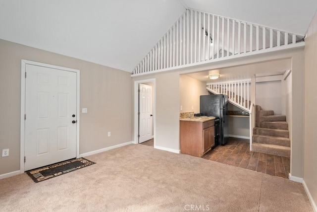 interior space with baseboards, dark colored carpet, high vaulted ceiling, and stairway