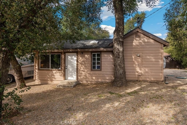 back of house featuring fence and roof with shingles