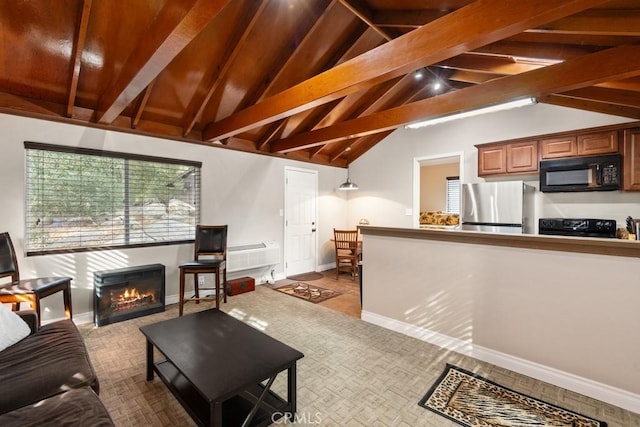 living area featuring a warm lit fireplace, vaulted ceiling with beams, and baseboards