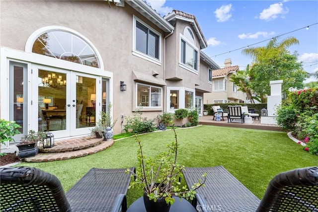 back of property featuring french doors, stucco siding, and a yard
