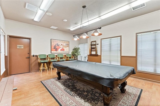 rec room with billiards, light wood-type flooring, a textured ceiling, and visible vents