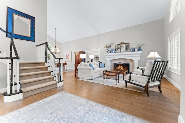 living room featuring stairway, baseboards, a fireplace, and wood finished floors