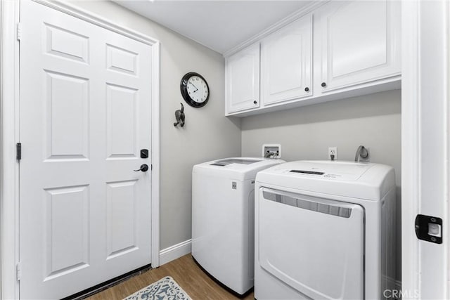 clothes washing area with cabinet space, baseboards, wood finished floors, and washer and dryer