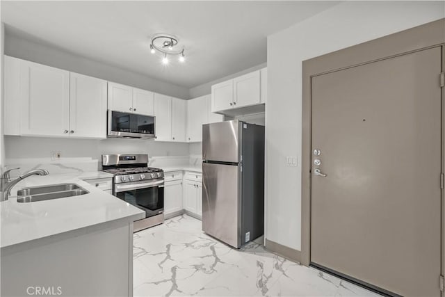 24535 Town Center Dr Unit 6309, Valencia, CA 91355 - kitchen with stainless steel appliances, a sink, light marble finish floors, white cabinetry, and baseboards