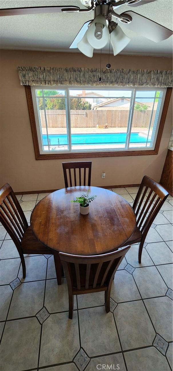 dining space with a ceiling fan and light tile patterned flooring