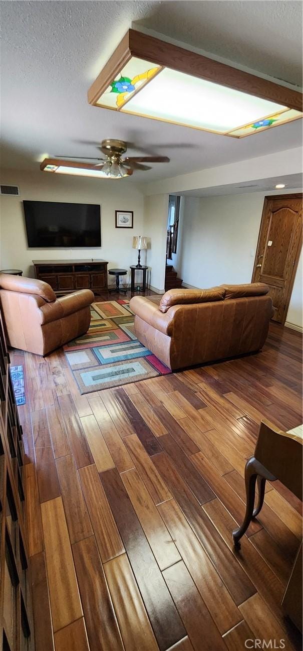 living room with wood-type flooring, a textured ceiling, visible vents, and ceiling fan
