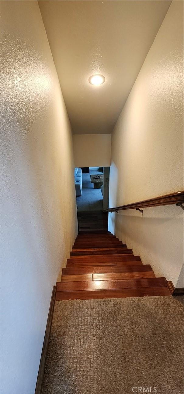 staircase with baseboards, a textured wall, and wood finished floors