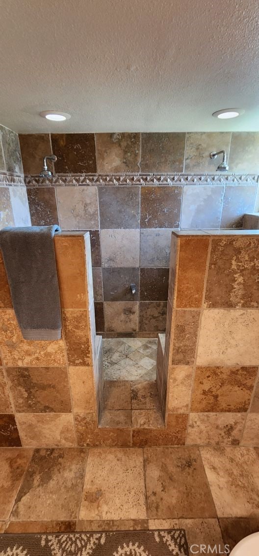 bathroom with a textured ceiling and a tile shower