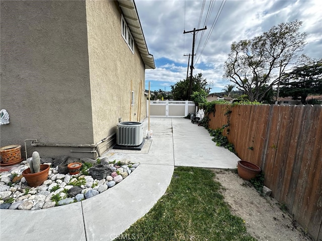 view of side of property featuring central AC, a fenced backyard, a patio area, and stucco siding
