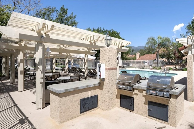 view of patio / terrace featuring a community pool, a pergola, exterior kitchen, and a grill