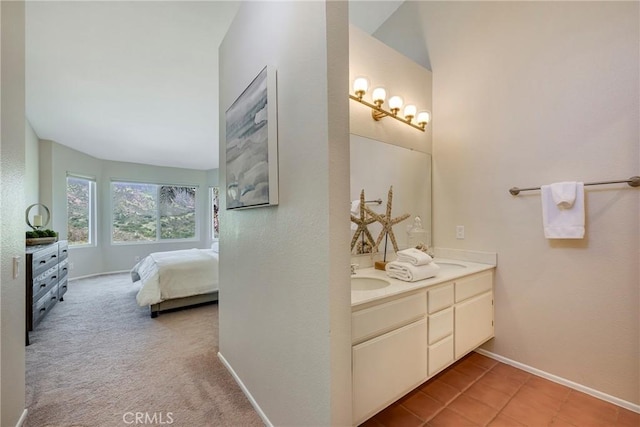 ensuite bathroom with double vanity, baseboards, a sink, and connected bathroom