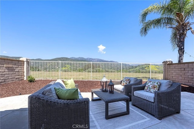 view of patio with fence, an outdoor living space, and a mountain view