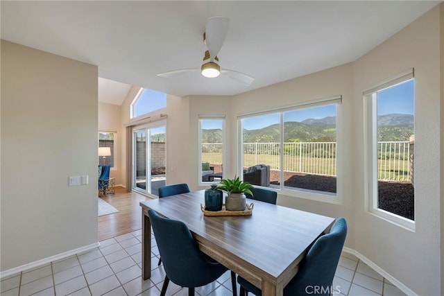 dining area with ceiling fan, baseboards, a mountain view, lofted ceiling, and light tile patterned flooring