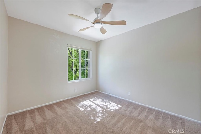 carpeted spare room featuring baseboards and ceiling fan