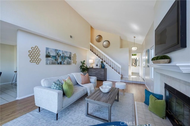 living area featuring visible vents, stairs, wood finished floors, and a tile fireplace