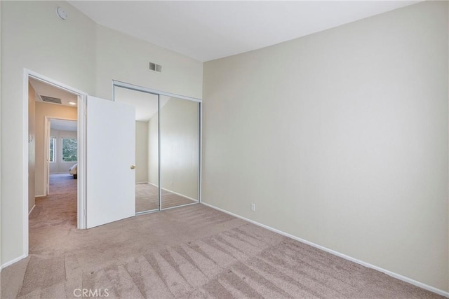 unfurnished bedroom with baseboards, visible vents, carpet, and a closet
